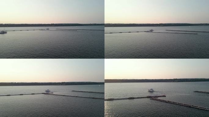安大略湖的日落，广阔的蓝色水面荡起涟漪，一艘白色的游艇在画面的左边行驶，在它的路径上留下了一个小的尾