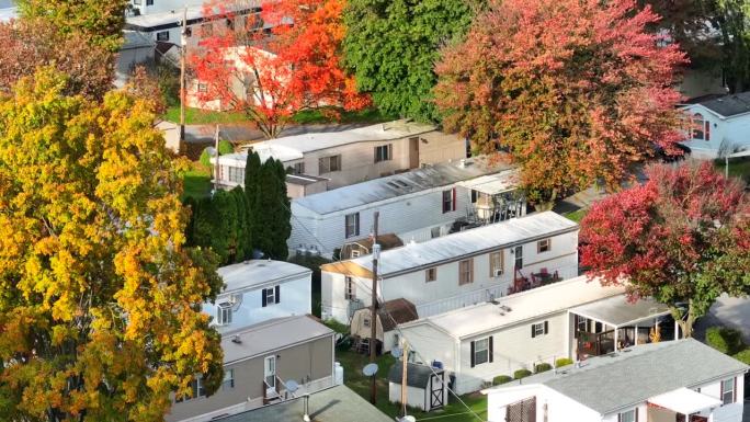 郊区有秋天树木的移动房屋。鸟瞰图拖车公园与五颜六色的树叶在秋天。