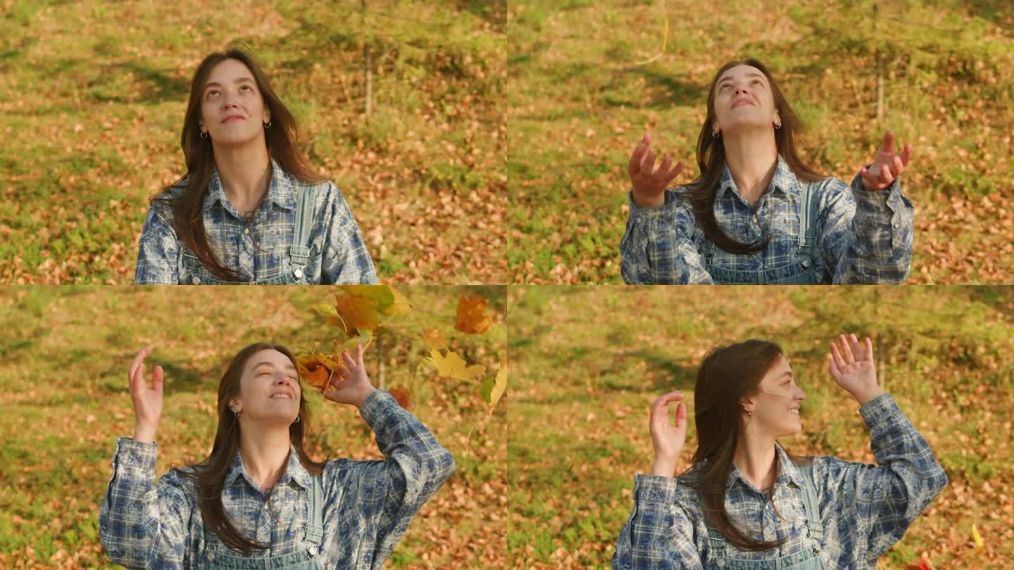 身穿蓝格子衬衫的年轻女子将枫叶扔过头顶(特写)。秋天的心情。季节变化。自然的户外