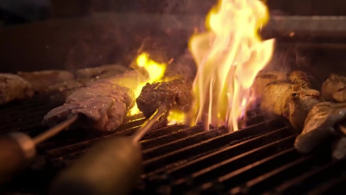 厨师准备烧烤肉在厨房烤架上明火近距离。美味多汁的肉烤在烤架上慢动作。烹饪烧烤食物的厨师。新鲜的鸡肉餐