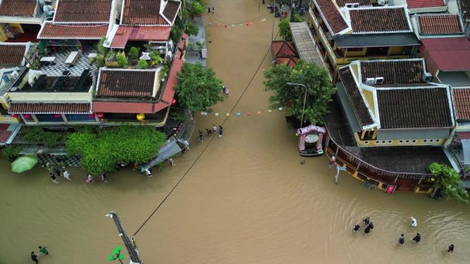 航拍画面显示，越南会安镇洪水过后，人们走在被水淹没的街道上
