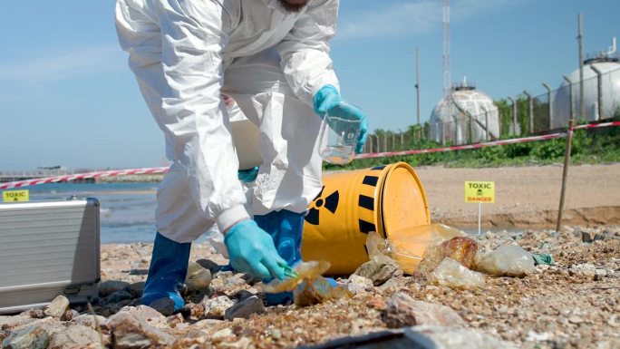 带着化学防护用品的工程师或科学家从炼油厂的油液中收集有毒物质，科学家检查有毒水样