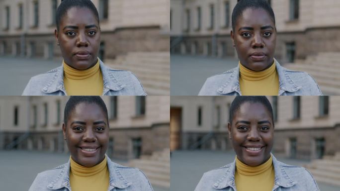 慢动作的非裔美国妇女看着镜头严肃的脸，然后微笑在城市外面