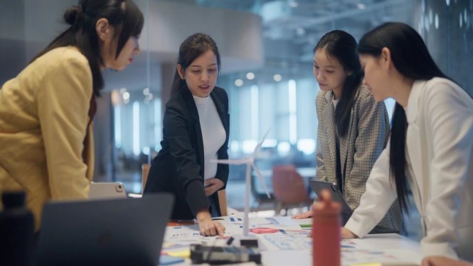 亚洲孕妇创意经理和她的团队在会议上讨论风能解决方案。