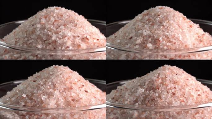 粉红色喜马拉雅盐或岩盐旋转在玻璃碗侧光。微量矿物质盐用于烹饪和食物展示，装饰灯和水疗