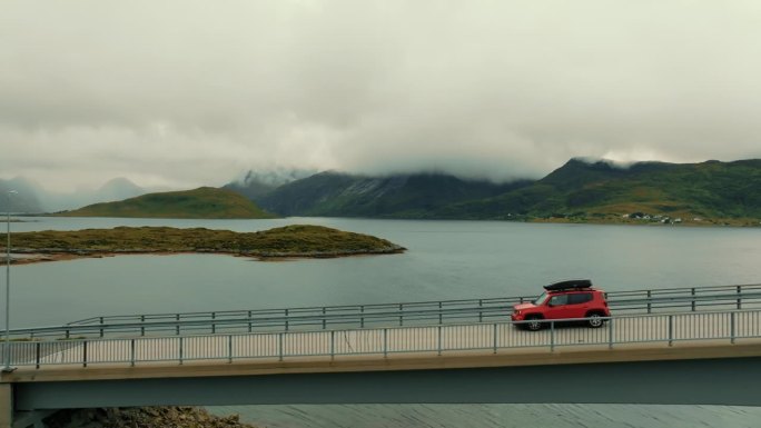 航拍侧视图，红色SUV轿车行驶在美丽的北欧景色的背景