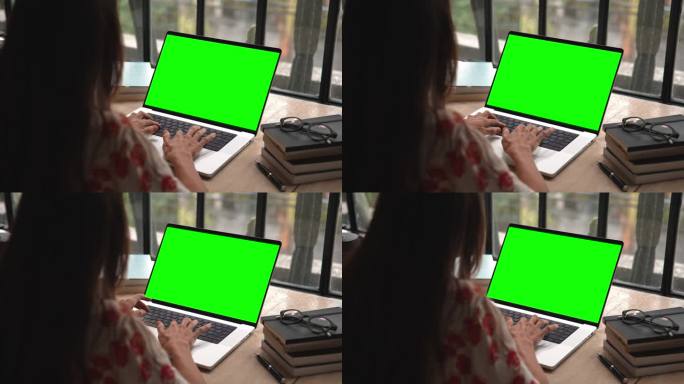 女人在笔记本电脑上工作，看着绿屏模型的色度键和视频通话。人的学习或聊天在网络讨论特写。观看视频通话或