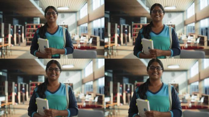 一个快乐的印度学生站在传统的公共图书馆的肖像。年轻的南亚女性看着镜头，微笑着。学者持有学术STEM和