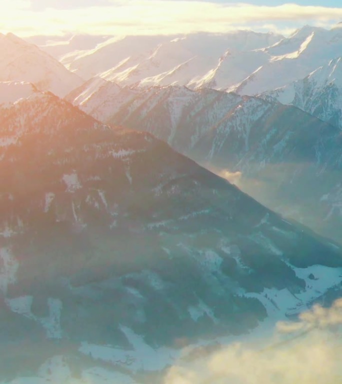 在一个阳光明媚的下午，空中直升机拍摄了宁静的乡村山区景观，白雪覆盖的山峰和奥地利阿尔卑斯山的滑雪胜地