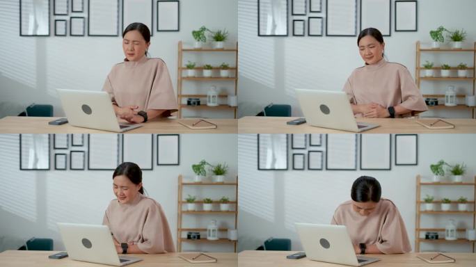 使用笔记本电脑工作的亚洲女性坐在家里办公室会感到胃痛。
