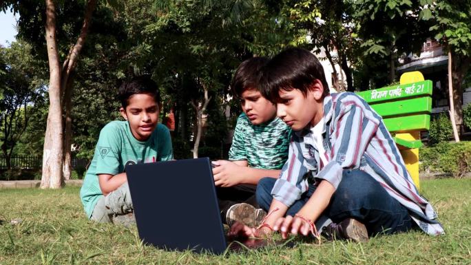孩子们在公园户外使用笔记本电脑，玩橡皮方块