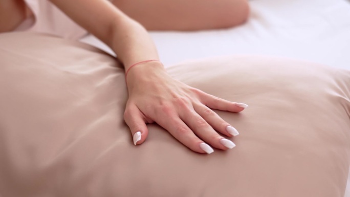 一个女人的手用手指抚摸着一个丝绸枕头(特写)