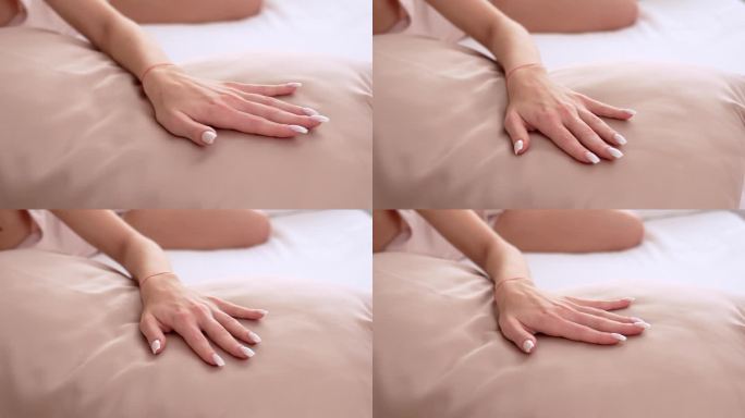一个女人的手用手指抚摸着一个丝绸枕头(特写)
