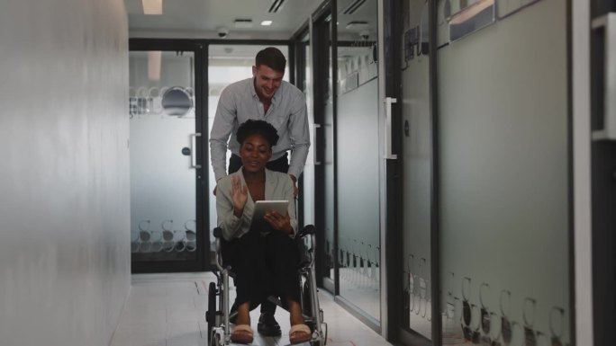 一位男同事帮助推着坐在轮椅上的女士。