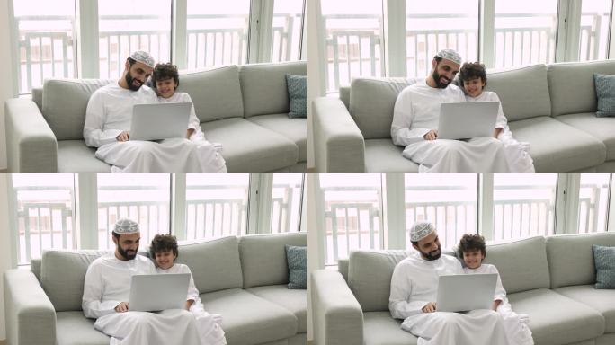 穆斯林男子带着儿子在笔记本电脑上看有趣的网络内容