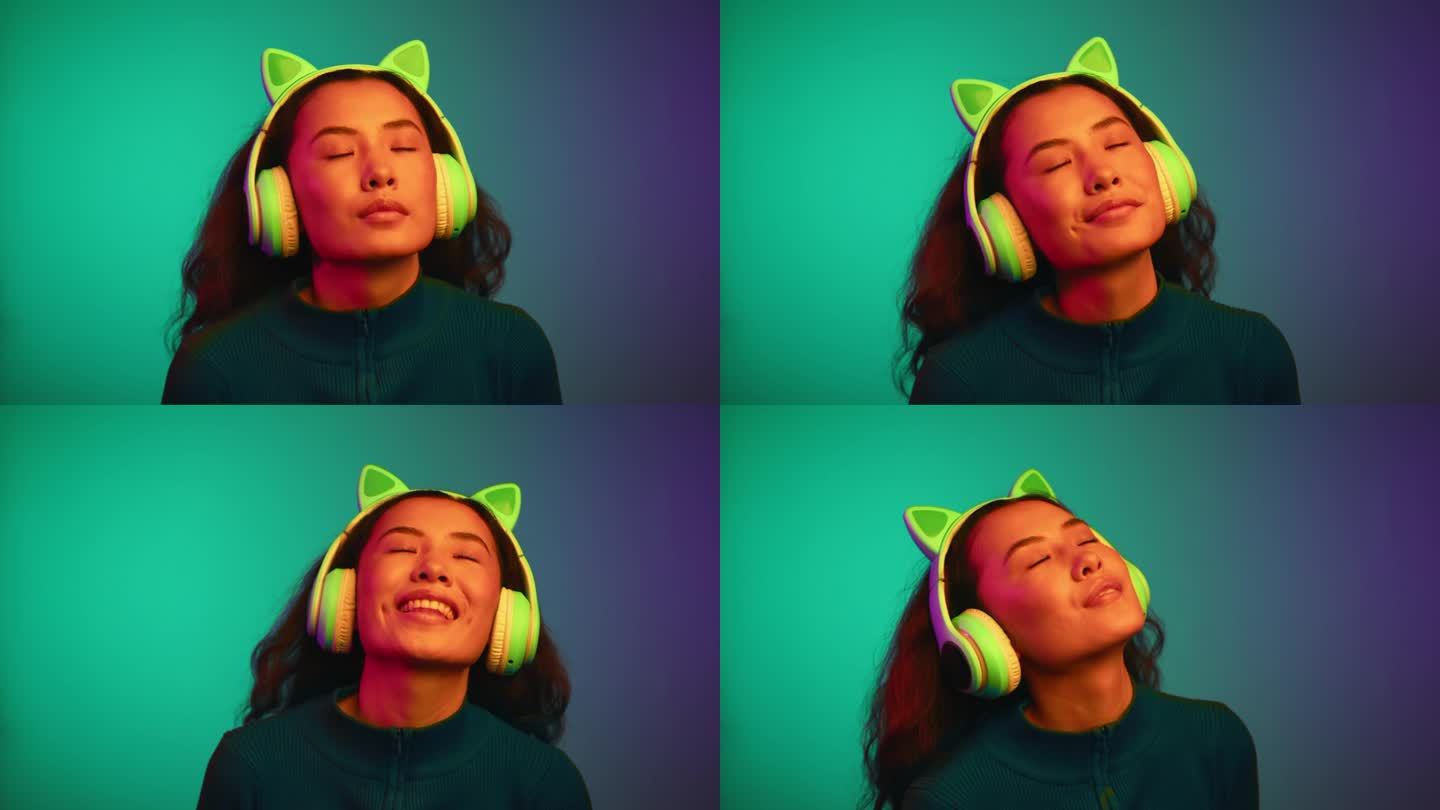 快乐的亚洲女人的肖像，戴着耳机，在霓虹灯下听音乐。一个微笑的女孩听着网络Mp3播放器上的在线歌曲。放