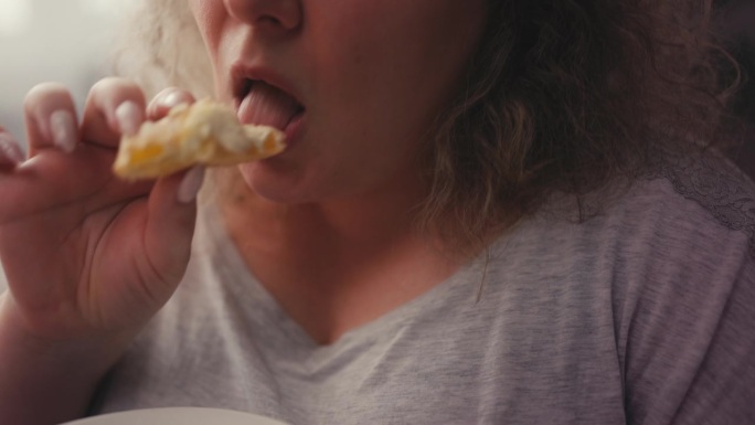 特写胖女人的嘴咬和咀嚼美味的蛋糕，饮食失调