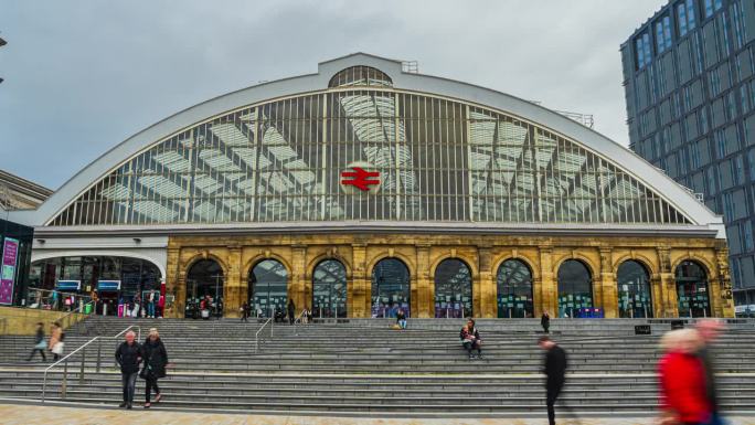 英国利物浦市莱姆街火车站拥挤的通勤人群步行和穿过街道交通的延时镜头