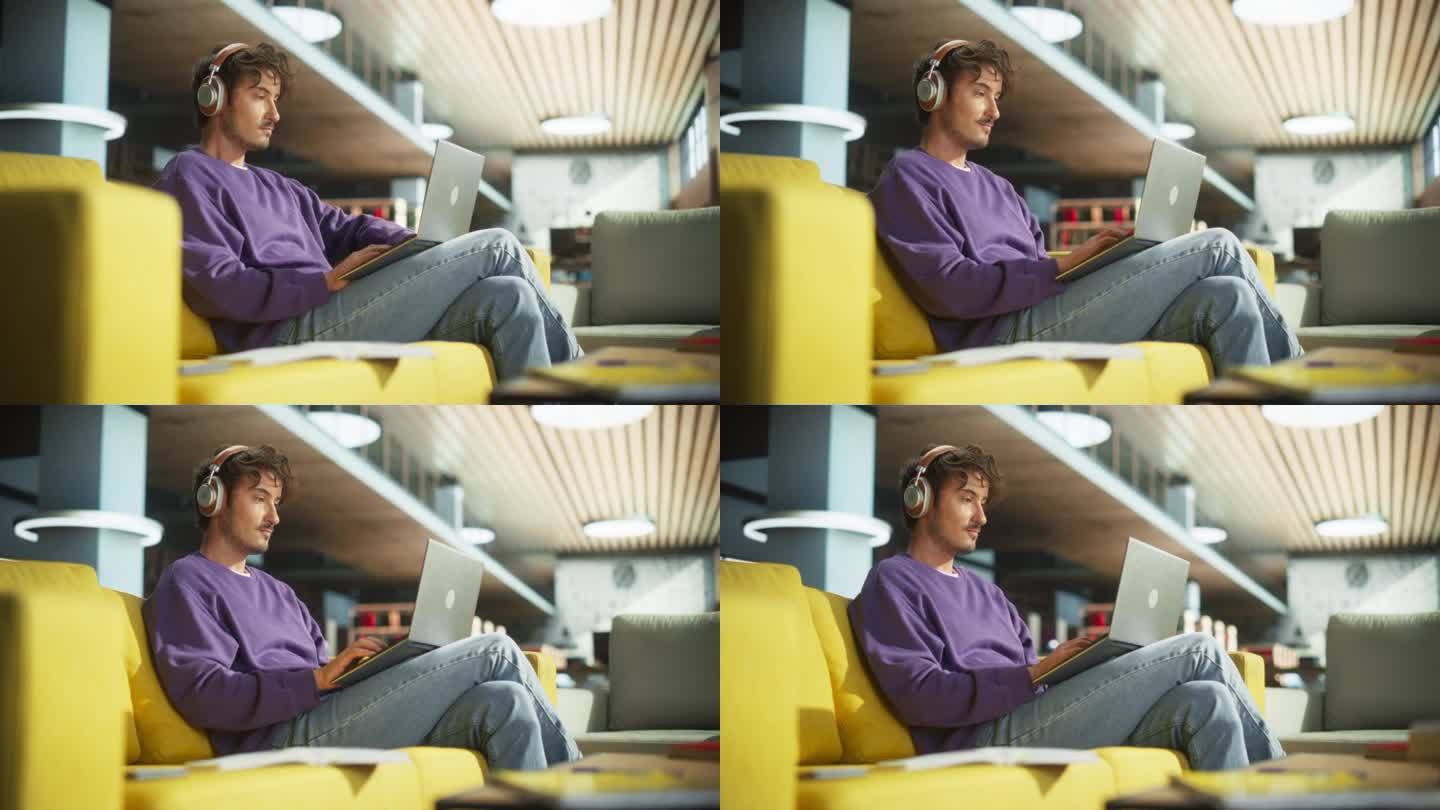 一个聪明的年轻人戴着耳机，在图书馆大厅用笔记本电脑工作。一个年轻人舒服地坐在沙发上，一边做作业，一边