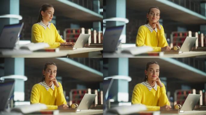 美丽的白人女学生在现代图书馆的笔记本电脑上写她的学校论文。年轻聪明的女人看着镜头，微笑着。穿着鲜艳的