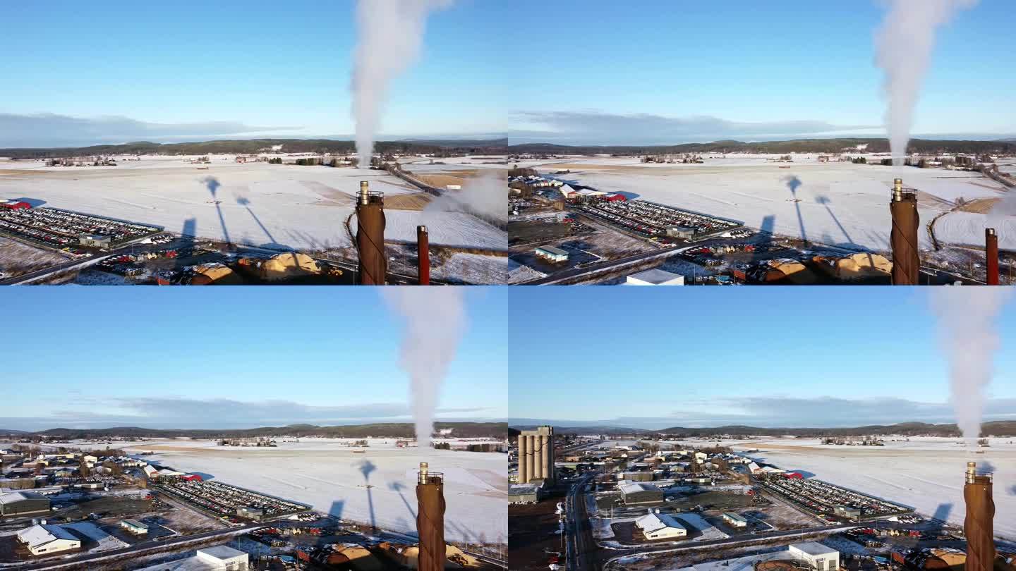烟囱散发出灰白色的烟雾，在工业区后面的雪地上投下长长的影子