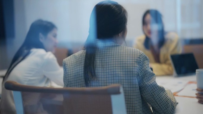 一位亚洲女商人在会议室里与同事进行头脑风暴的特写。
