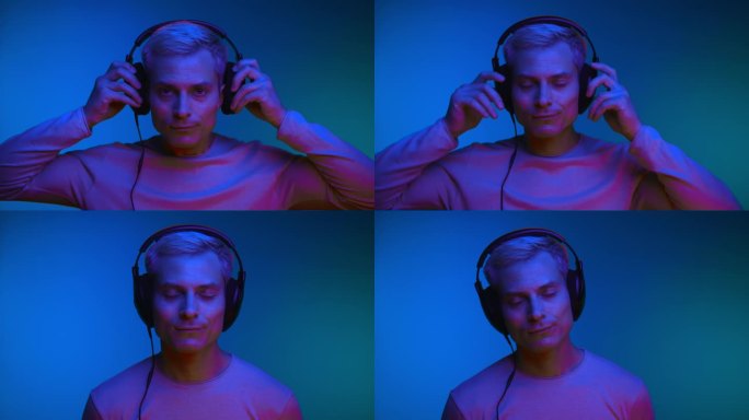 在室内拍摄的霓虹灯下，戴着耳机听音乐的人的肖像。一个时髦的家伙听到网络播放器的在线音频。时髦的模特在