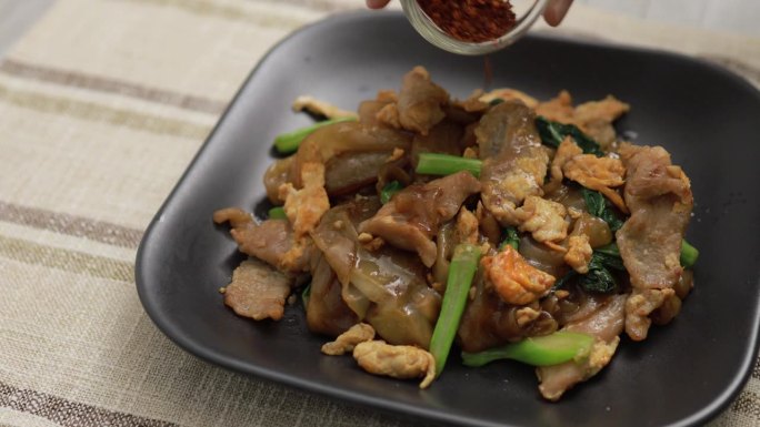 泰国街头小吃，厨师正在调味和混合泰式炒面与酱油(Pad See Ew)盘