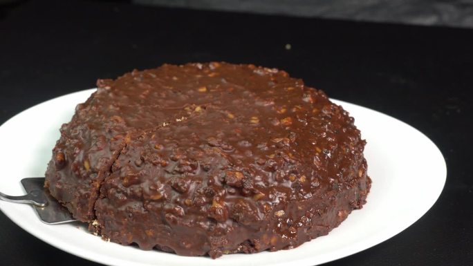 厨师用锅铲铲起一块巧克力蛋糕，端给客人。自制蛋糕或甜点