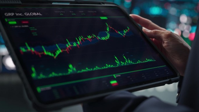 近距离镜头的平板电脑显示器屏幕与实时股票，商品，交易市场图表显示在一个金融业务办公室