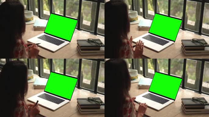 女人在笔记本电脑上工作，看着绿屏模拟色度键和视频通话。远程办公和讨论聊天特写。观看视频通话或阅读We