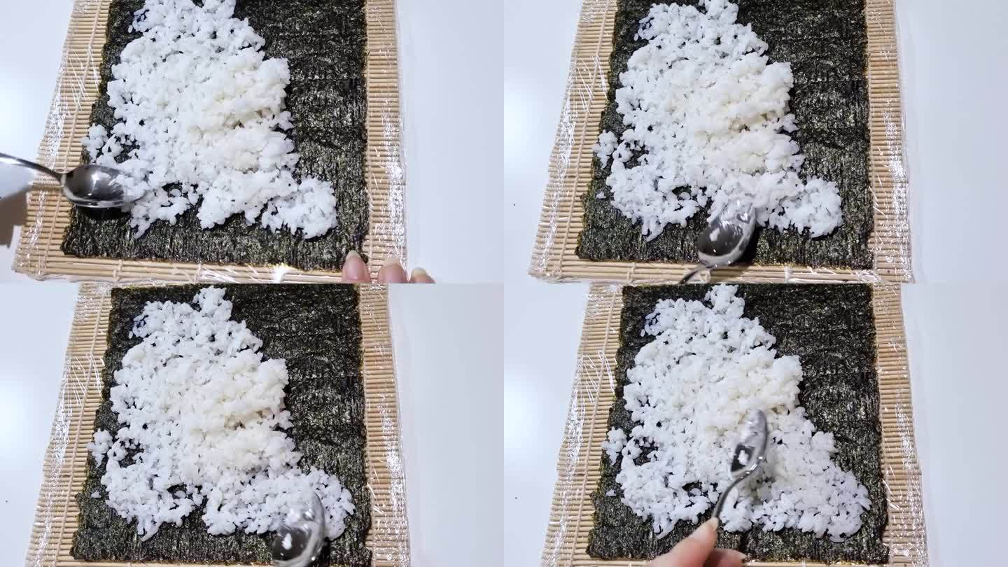 制作寿司时，将米饭放在海苔片上