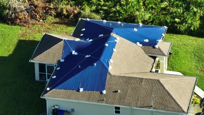 飓风伊恩损坏了屋顶，屋顶上覆盖着防止雨水泄漏的塑料布，直到更换沥青瓦。自然灾害后的后果