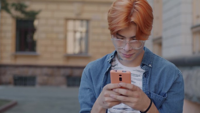 慢镜头，快乐的亚洲男子用智能手机查看社交媒体内容，在城市户外开怀大笑