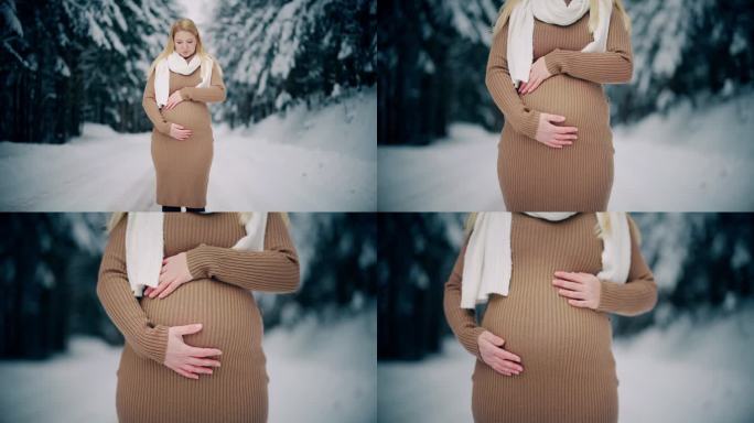 美丽的孕妇在白雪皑皑的森林里揉着肚子
