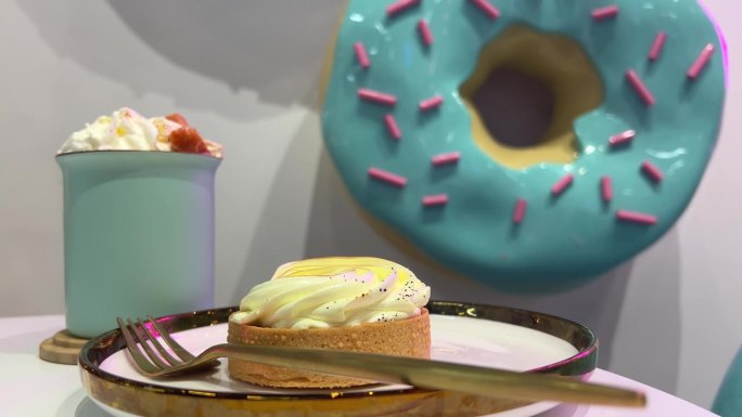 咖啡馆里有饮料和馅饼，背景是一个巨大的蓝色甜甜圈，上面点缀着粉红色的装饰