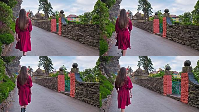 一个穿着红裙子的漂亮女孩参观了波特梅里恩村。