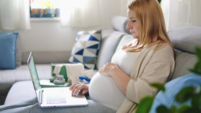 孕妇在家里客厅沙发上用笔记本电脑工作
