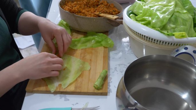 做包心菜的女人小心地把碾碎的混合物放进包心菜里。