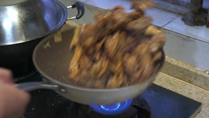厨房里的厨师正在煎鸭肉，用酱汁炒鸭肉