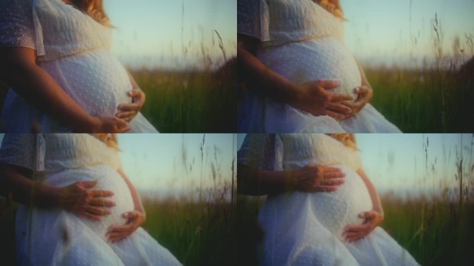 近距离拍摄身穿白色礼服的孕妇在野外按摩腹部