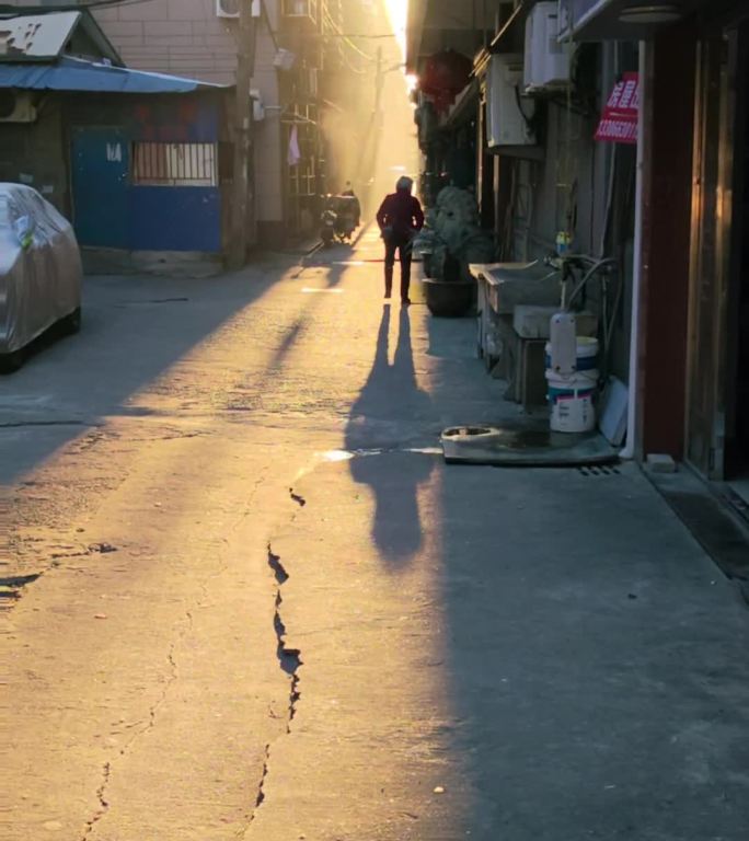 夕阳下一位老人在小巷子里缓慢地走着
