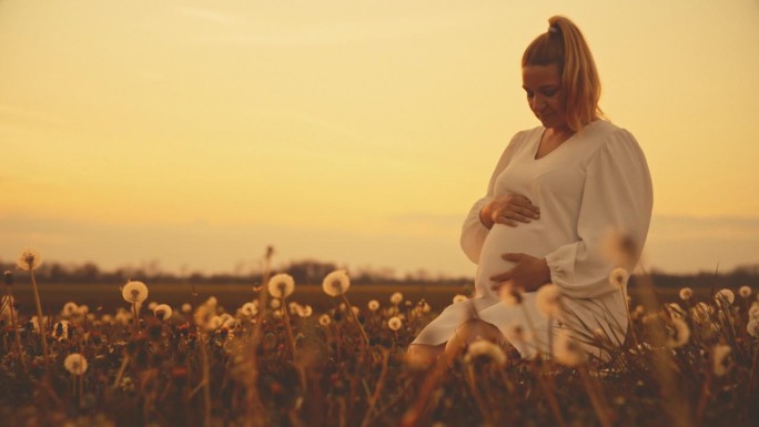 一名身穿白衣的孕妇在农村按摩婴儿肚子