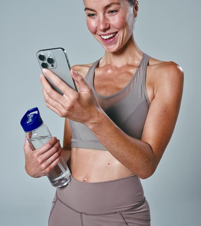 垂直视频工作室拍摄的女人在健身房健身服装与运动垫和水瓶