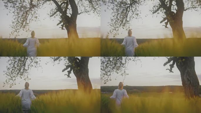 一位身穿白衣的孕妇走在树下宁静的田野里