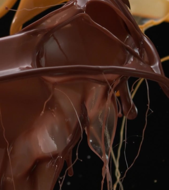 巧克力焦糖和牛奶滴的超级慢动作飞溅，巧克力碎片落入混合物中