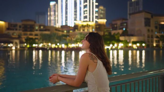 一名女子晚上走在迪拜哈利法塔和迪拜喷泉附近