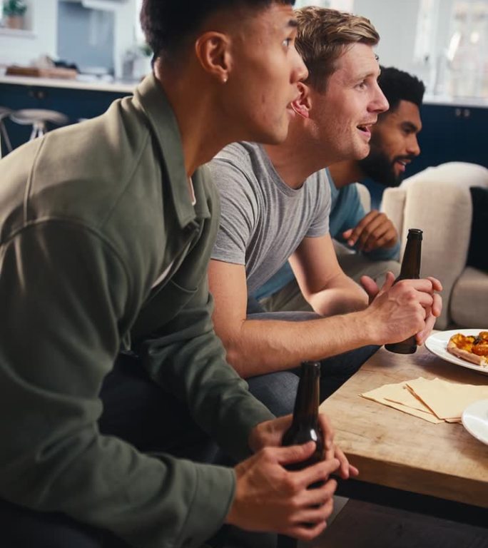 一群失望的男性朋友在家里看电视上的体育比赛和披萨的垂直视频