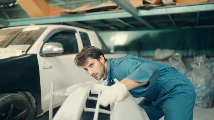 熟练的拉丁机械师在车间车库修理事故后的汽车车身。