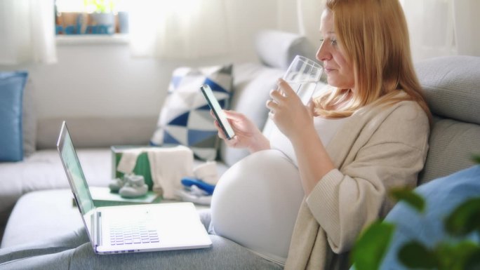 孕妇喝水，在家用笔记本电脑工作